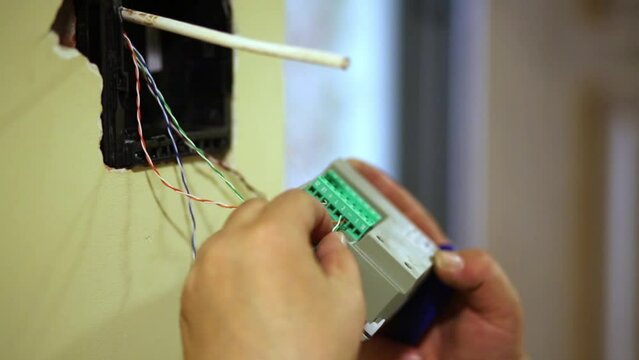 Worker connects wires to external block of home intercom.