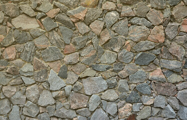 The texture of a strong stone wall of many concreted stones of various shapes