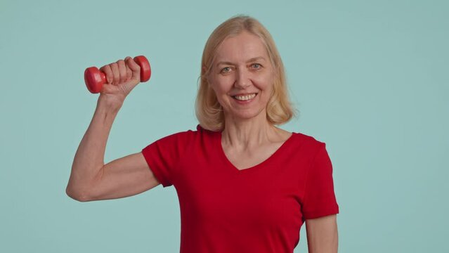 Active senior woman posing with dumbbells in hands and siling . studio shot 