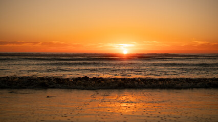 Fototapeta premium Beautiful beach with rays of sun reflected in the foam of the waves