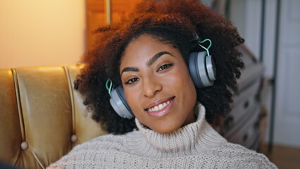 Cheerful model listening headphones portrait. Happy curly woman smiling camera