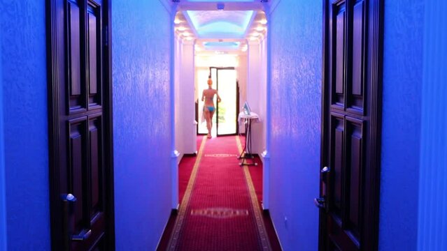 Back of woman in swimsuit going in corridor of hotel