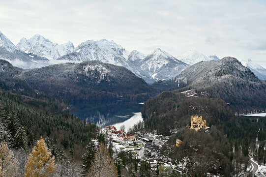 landscape with snow covered trees. Alpsee with castle next to it.