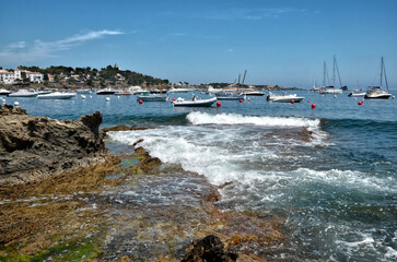 Rocky coastline with waves and boats at Cadaqués, commune on the Costa Brava at northeastern Catalonia in Spain