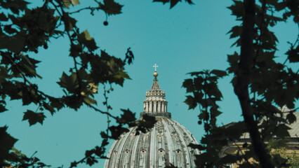 The detailed view of dome summit of Papal Basilica of St. Peter in the Vatican against blue sky and...