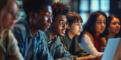Fototapeta premium Young interracial college students in class while doing group work on a table with a computer