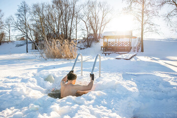 Man embracing the cold in an ice swimming hole during a sunny winter day
