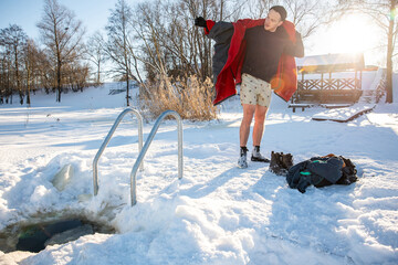 Man drying off  after cold winter swimming in the golden sunlight of a snowy landscape