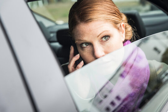 Businessfrau telefoniert und schaut aus Autofenster , M&uuml;nchen, Deutschland