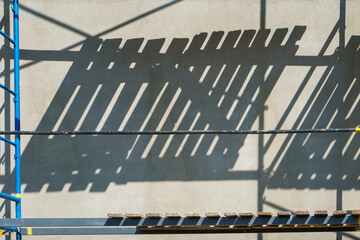 Scaffolding is installed along the wall of the building under construction. Plastering and painting...