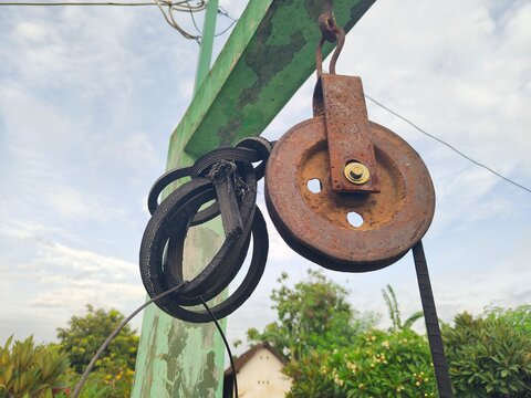 And old rusty pulley with worn rope made of rubber which people use to take water from well in village