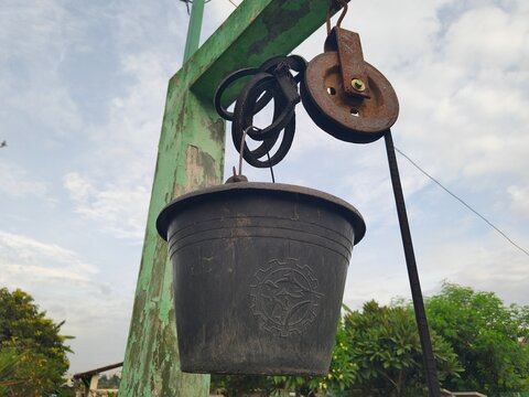And old rusty pulley with worn rope made of rubber which people use to take water from well in village