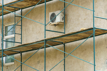 Scaffolding is installed along the wall of the building under construction. Plastering and painting...