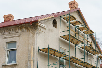 Scaffolding is installed along the wall of the building under construction. Plastering and painting...