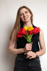 Portrait of young pretty woman, smiling and holding beautiful bouquet of flowers red tulips on white background. Spring, happiness and celebration concept.