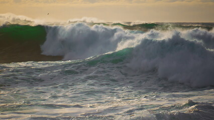 Dramatic stormy ocean waves splashing on sunny day. Extreme seashore landscape