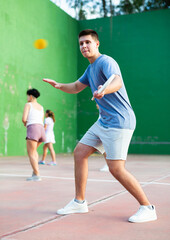 Concentrated young man paleta fronton player hitting ball with a racket