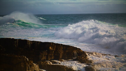 Huge waves breaking rocky beach in super slow motion. Powerful sea surf rolling