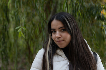 Mujer joven misteriosa sonriendo en un entorno natural repleto de naturaleza