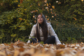 Un momento de paz: una joven atractiva disfruta de la belleza del otoño entre las hojas - obrazy, fototapety, plakaty