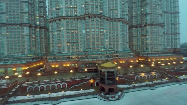 Residential complex and illuminated quay on shore of icy river