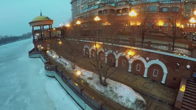 Illuminated quay with people near dwelling complex at winter