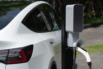 EV electric car charging in green sustainable city outdoor garden in summer. Urban sustainability...