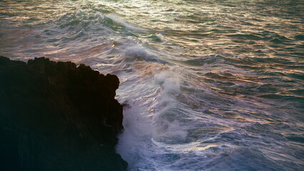 White waves hitting rocks on evening. Stormy ocean breaking wash volcano beach