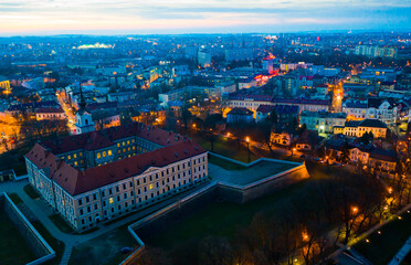 Aerial view of Renaissance building of Rzeszow castle on background of lighted cityscape at twilight, Poland