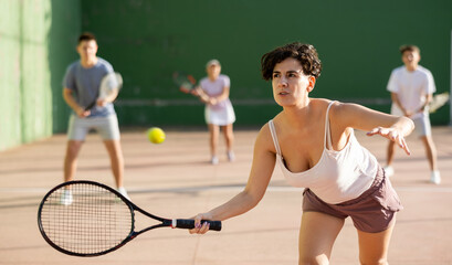 Latin woman playing frontenis on outdoor pelota court during training. Woman playing Basque pelota...