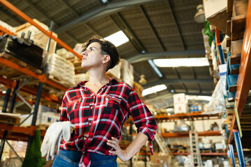 Thoughtful female storekeeper looking for tedious goods in building materials warehouse