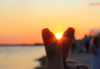 Silhouette of fingers sign, mini heart on sunset sky at the seaside. Korean body language symbol of...