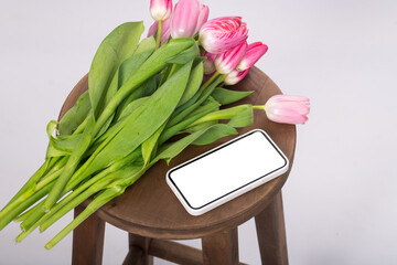 a bouquet of pink tulips lies near the smartphone. place for text
