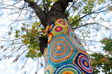 yarnbombing tree with baubles in the winter with blue sky background