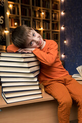A boy of Slavic appearance sits near a stack of books. in the background of the library. vertical photo
