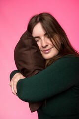 a woman of Slavic appearance hugs a pillow with closed eyes