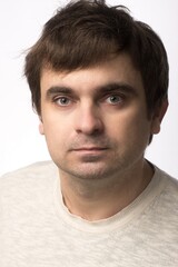 Obraz premium Portrait of a man with a neutral expression, wearing a light beige sweater. The subject is in focus with a plain white background, offering a professional and clean look, ideal for stock use