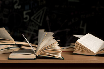 Open books on a wooden table with pages flipping in the air. Concept of knowledge, education, literature, and learning. Dim background creates an intellectual and focused atmosphere