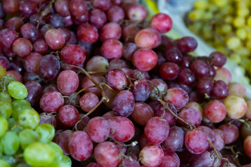Red grapes put on counter for sale alongside with other products in fruit and vegetable market