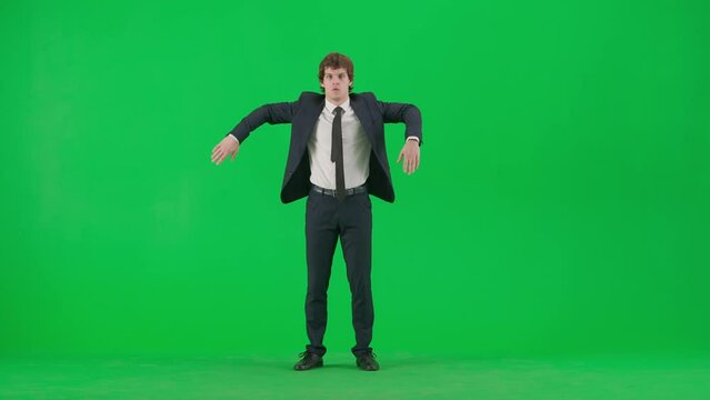Portrait of male model in suit on chroma key green screen. Handsome young businessman in trendy suit dancing old school robot dance.