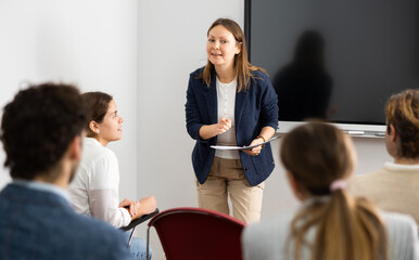 Experienced female teacher giving lecture to group of student
