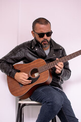 Aesthetic photo of an attractive, bearded hipster playing acoustic guitar outdoors at sunset.  acoustic guitar. Teacher.