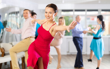 Fototapeta premium Positive adult pairs practicing vigorous jive movements in dance class