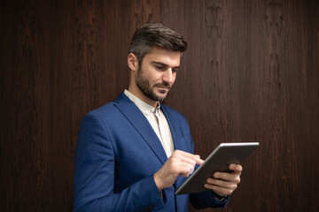 Company leader in business suit using tablet computer in the company office.