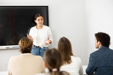 Fototapeta premium Young female professor explaining subject to classroom full of students