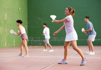Young sporty woman performing basic strokes during paleta fronton group training