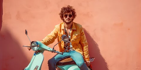 Photo sur Plexiglas Moto A young vintage style biker man is posing riding a retro vespa type motorcycle, with a peach fuzz colored wall in the background