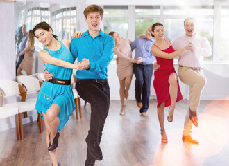 Group is of different ages active people engaged in Latin dance studio and learns movements of...