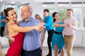 Adult woman and old man dancing in dance class