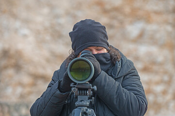 Woman birdwatching with a telescope in cold weather.